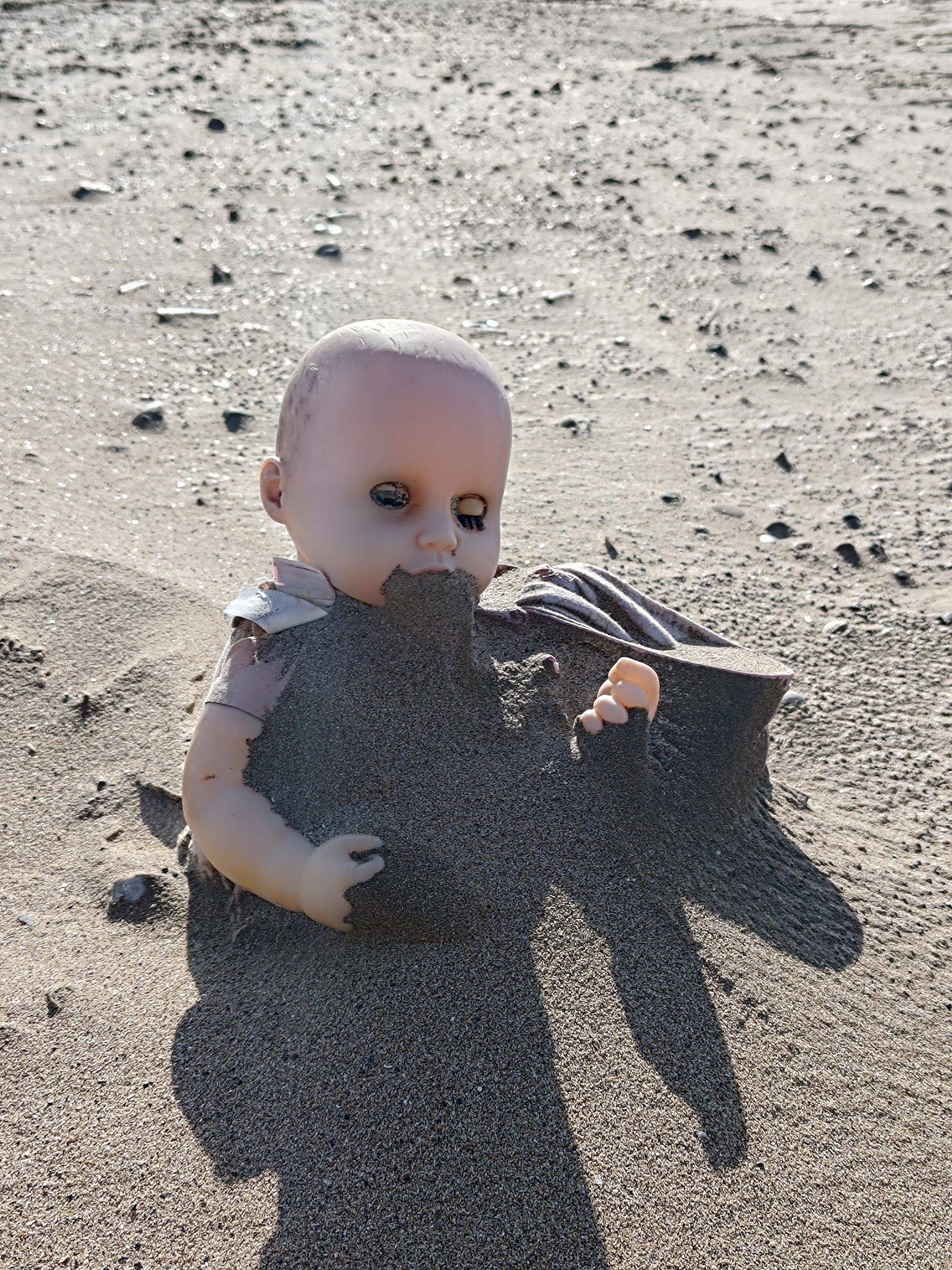 Creepy doll in sand by Bon Arte Photography