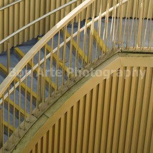 Gold geometry print capturing a minimalist helical staircase and textured metallic facade lines