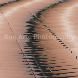 A minimalist square geometric composition of repeating copper metallic panels with sharp lines and deep shadows, ideal for electronic music album cover layouts.