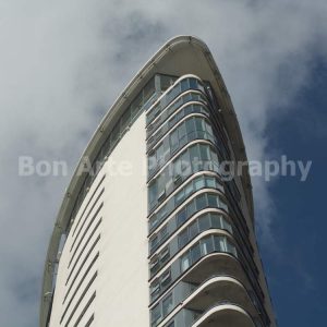 Modern minimalist tower architecture photo showing a curved glass facade against a cloudy sky for ambient album cover design by Bon Arte Photography.
