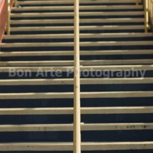 A symmetric staircase thriller cover stock photo featuring a vertical view of concrete stairs with a central metal handrail and hard shadows by Bon Arte Photography.